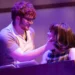 Two performers on stage share a close moment during 'Beautiful', illuminated by purple lighting.